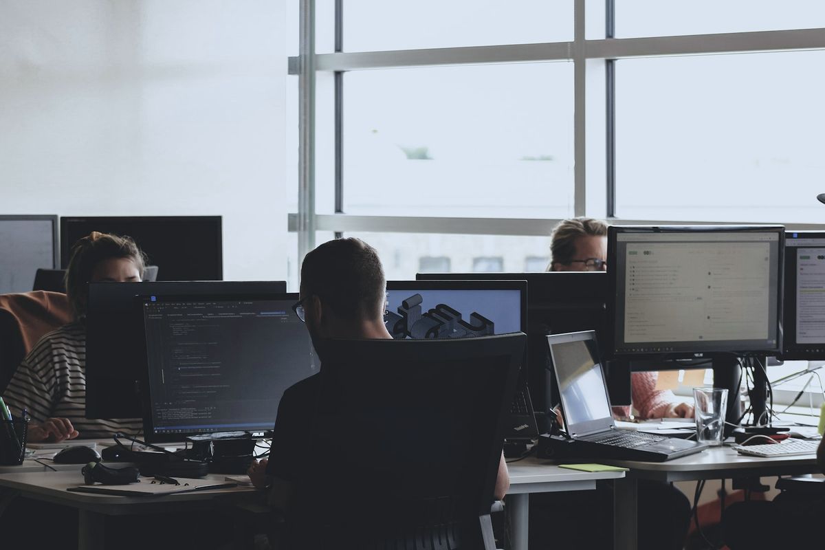 Support-Team arbeitet an mehreren Monitoren in einem hellen Büro
